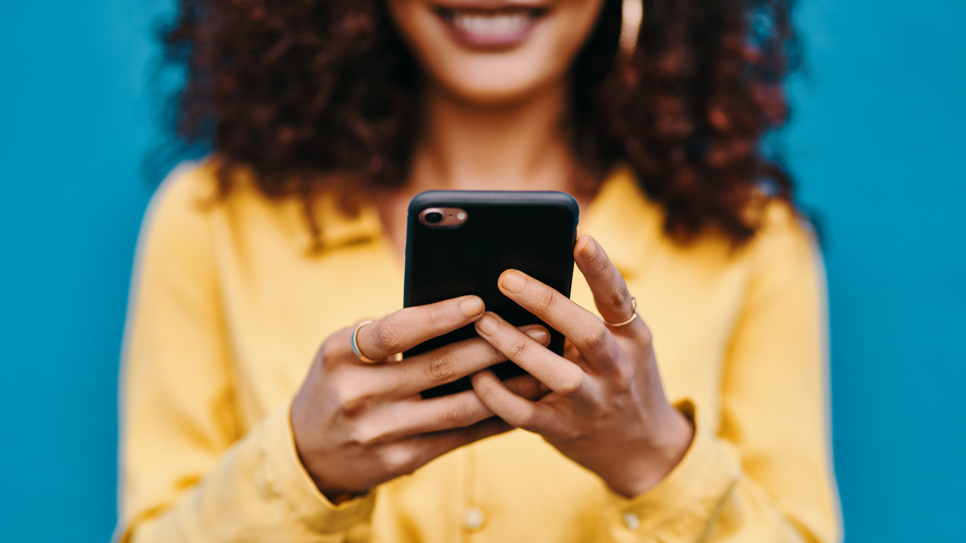 Woman in a yellow shirt holding a phone into focus